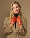 Women's orange lambskin driving gloves with perforated finger panels and snap wrist