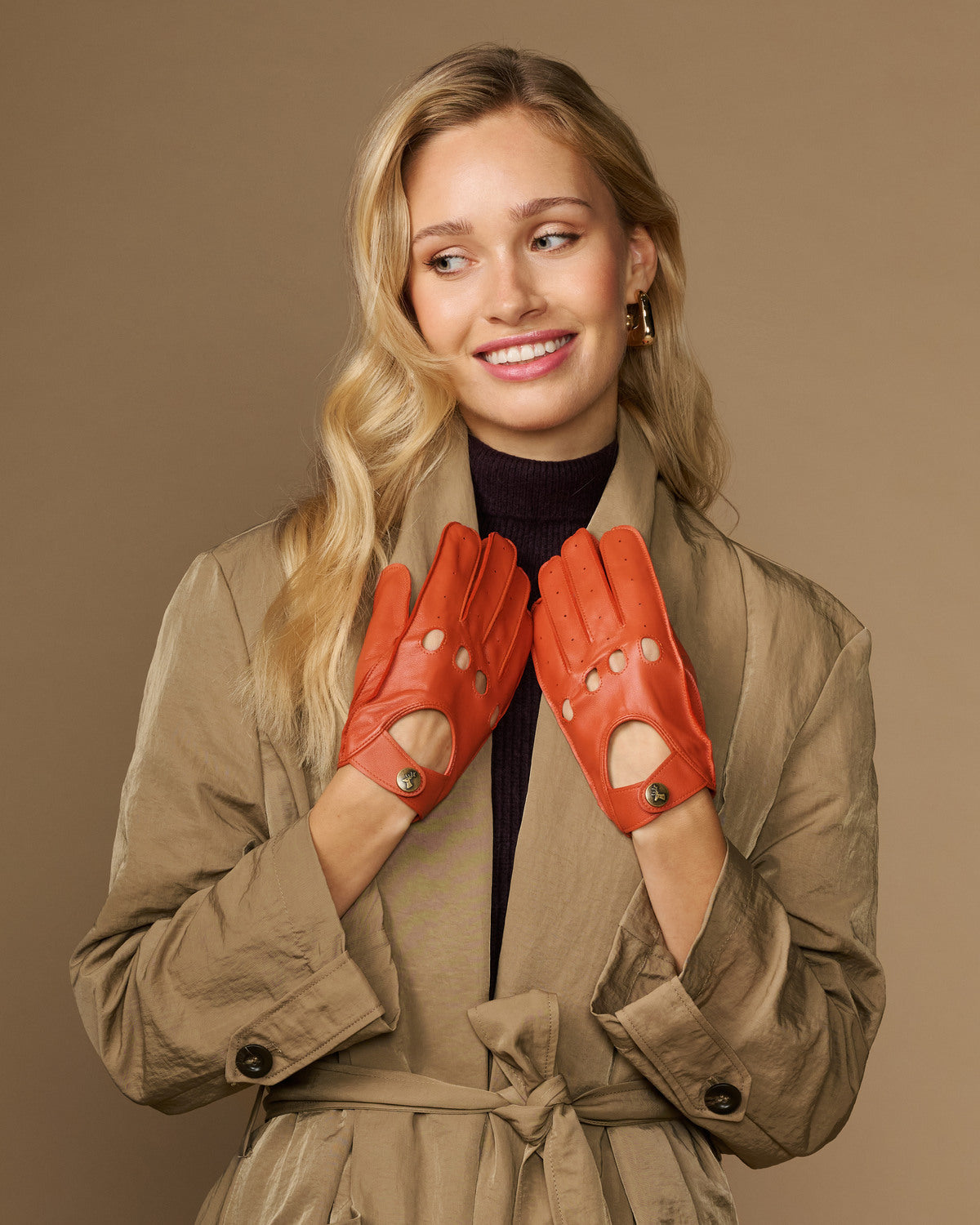 Women's orange lambskin driving gloves with perforated finger panels and snap wrist
