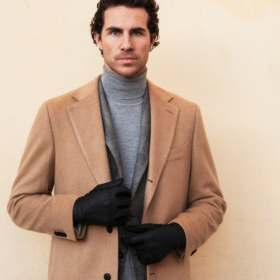 Man wearing dark leather gloves while holding his hands together