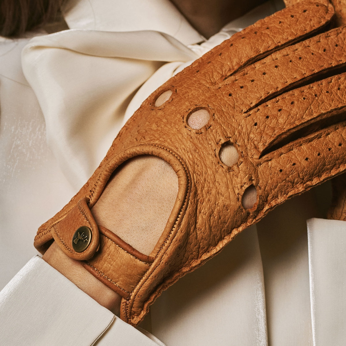 Cognac leather glove palm with oval patch, perforations, and snap wrist strap