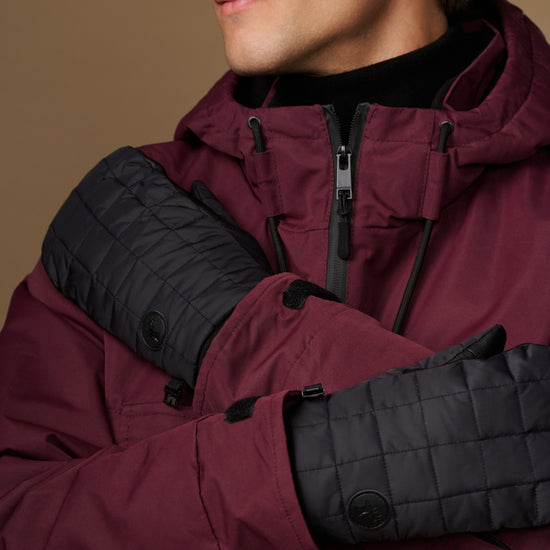 Close-up of black quilted mittens with snap details and extended cuffs.