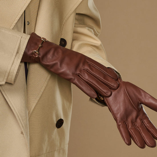 Dark brown leather glove with gold-tone buckle strap and stitched finger seams