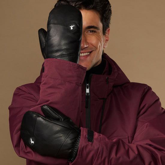 Black leather men's winter mittens, shown worn with smooth panels and small logo patches.