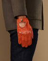 Orange lambskin touchscreen glove, worn at side with thumb opening