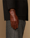 Cognac leather glove close-up with fleece-lined cuff and stitched finger panels