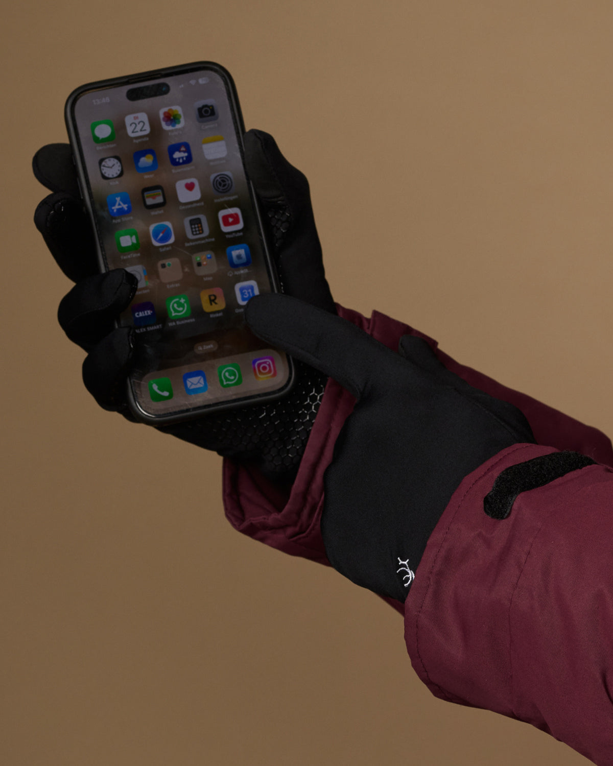 Black touchscreen-compatible activity gloves used to operate a phone