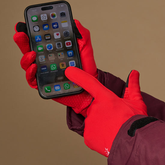 Red activity gloves with textured grip palms, used to operate a smartphone