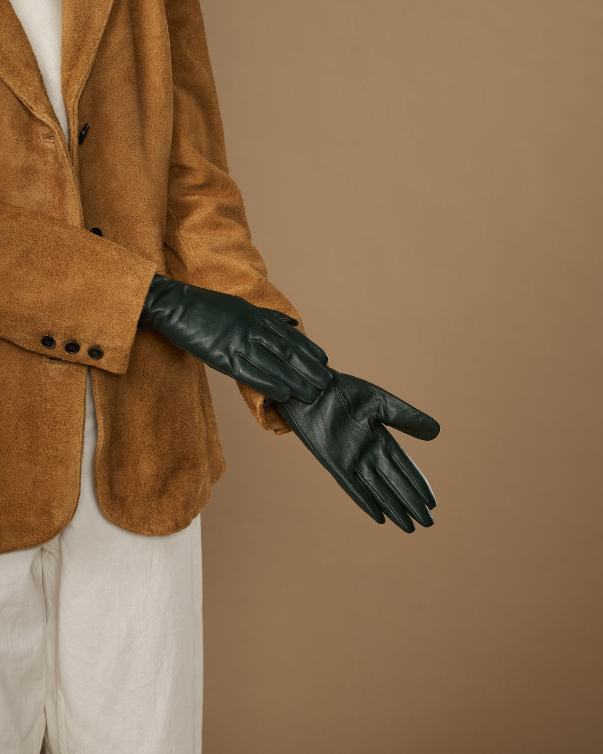 Single dark green leather glove stretched out, showing finger seams and stitched cuff