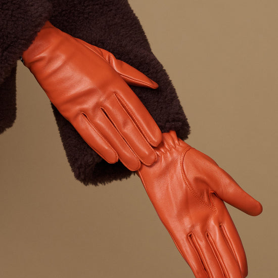 Lauren orange lambskin leather glove close-up, touchscreen tips, silk-lined seam detail