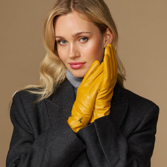 Yellow leather gloves worn with stitched knuckles and a snug wrist cuff