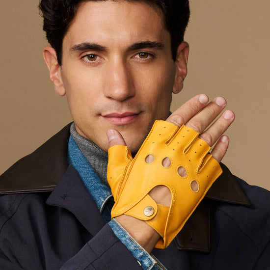 Yellow fingerless driving glove with perforated knuckles and snap cuff detail