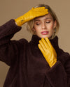 Yellow leather gloves with dark fleece cuff, held up near the face