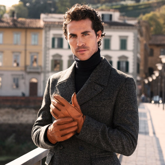 Man holding hands together wearing cognac brown peccary leather gloves