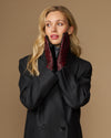 Women's black leather gloves with red-and-black checkered lining, worn at neckline