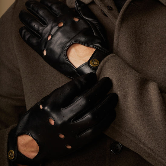 Close-up of black leather driving gloves with stud details and touchscreen thumb panel