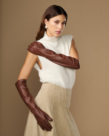 Women’s elbow-length brown lambskin leather gloves with silk lining, worn.
