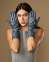 Pair of grey-blue mid-forearm leather gloves with glossy leather texture