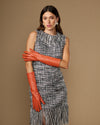 Women’s orange below-elbow leather gloves, one glove draped at side