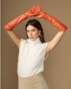 Orange leather elbow gloves worn with arms raised, covering hands and forearms