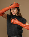 Orange lambskin leather gloves with silk lining and touchscreen tips, hands on head
