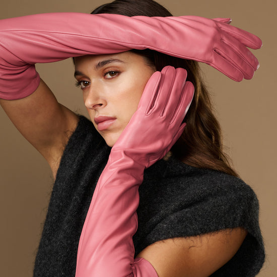 Women's pink leather gloves with extended wrist and fingers, side pose