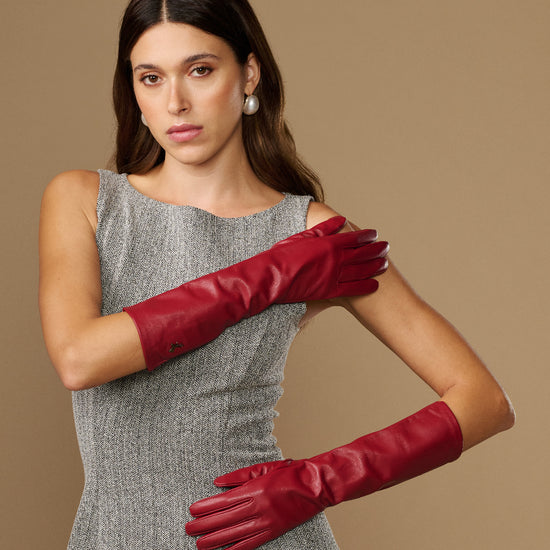 Red leather gloves worn on both arms, featuring snug wrist cuffs and tailored fingers