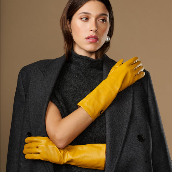 Yellow leather gloves with smooth surface and mid-forearm length, hand detail