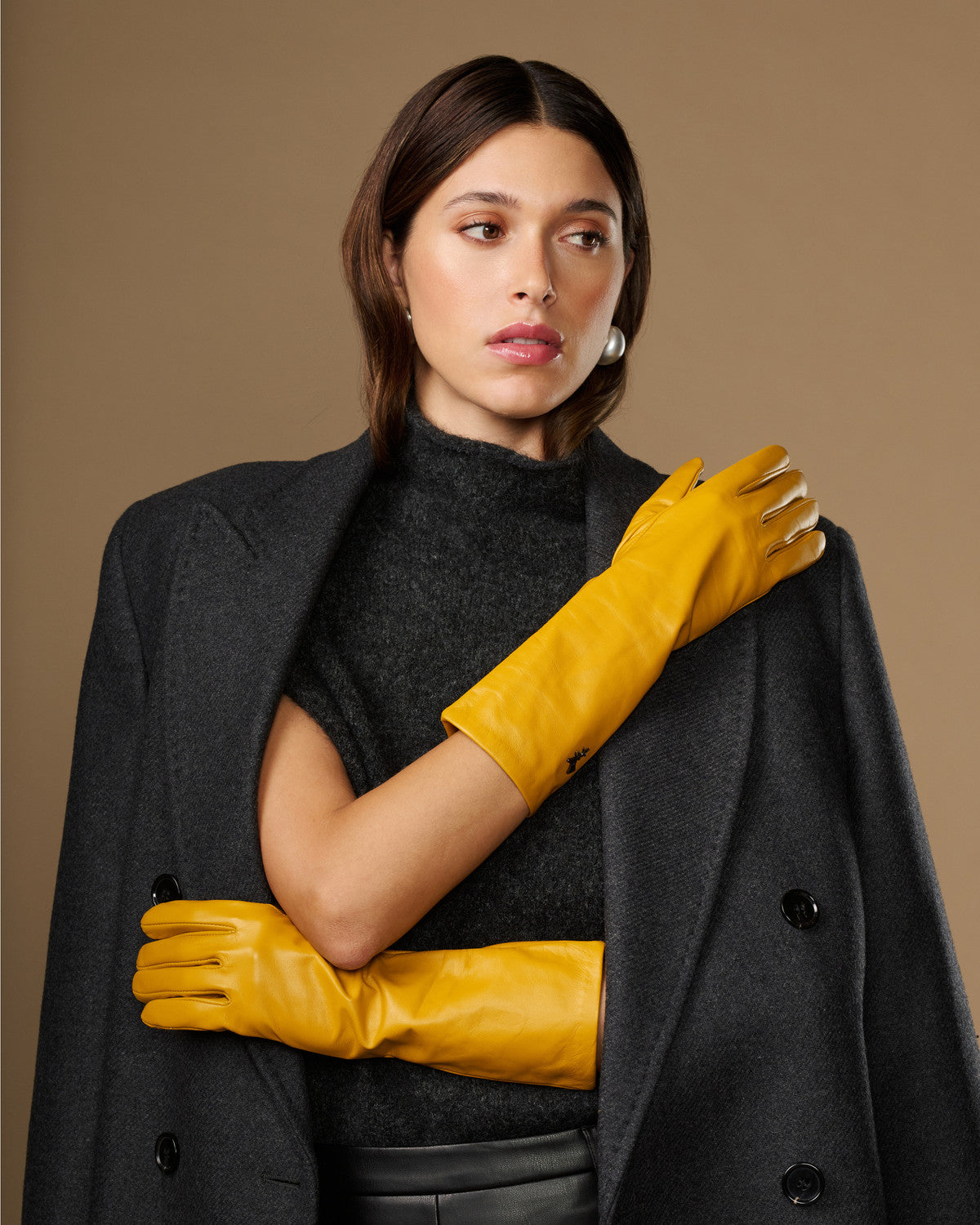 Yellow leather gloves with smooth surface and mid-forearm length, hand detail