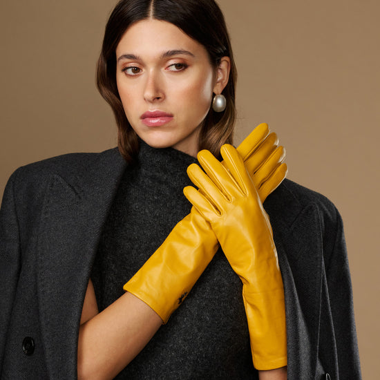 Yellow leather gloves with close-fitting cuffs and stitched fingers, mid-forearm length