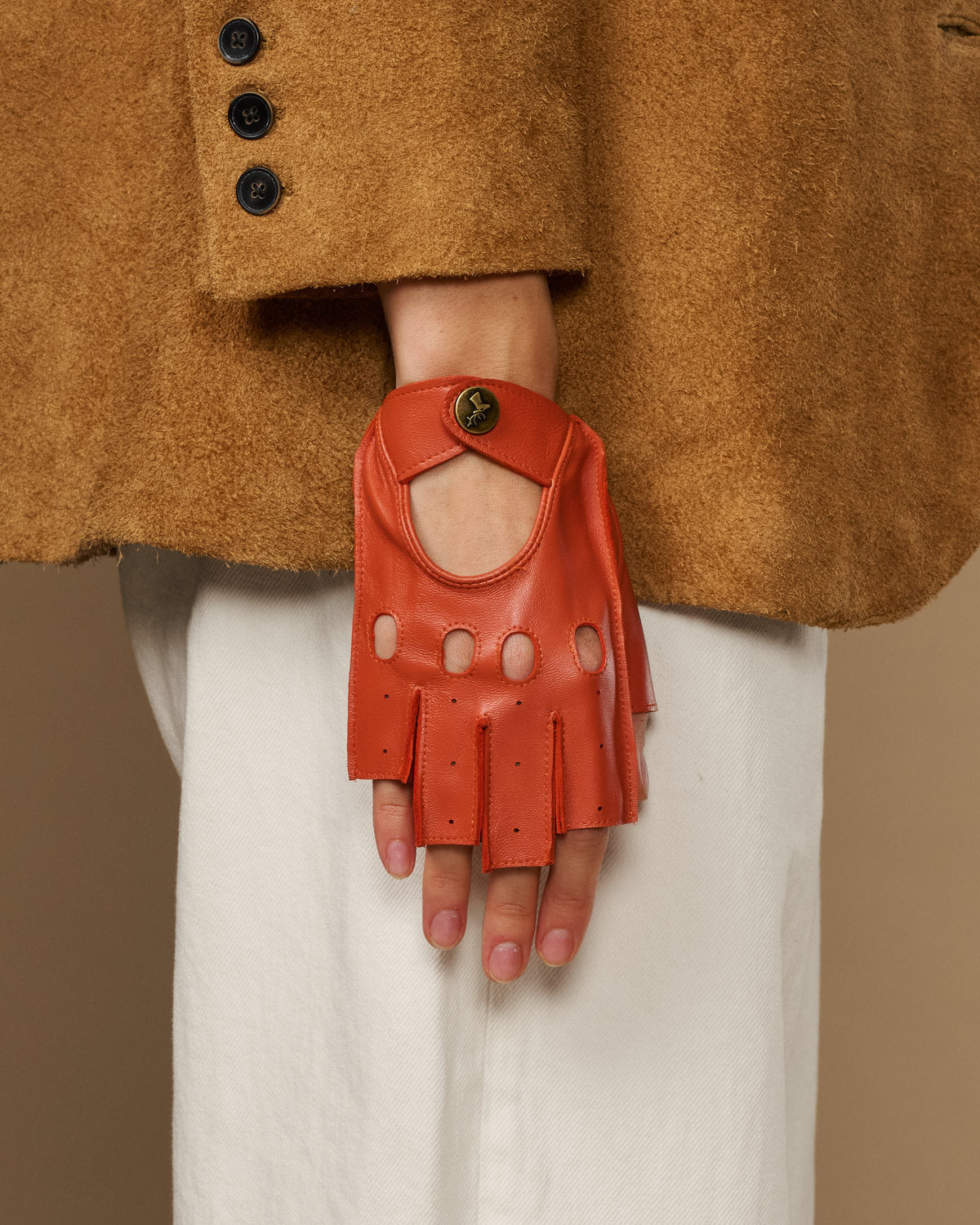 Orange fingerless glove with finger holes, thumb opening, and round logo wrist button