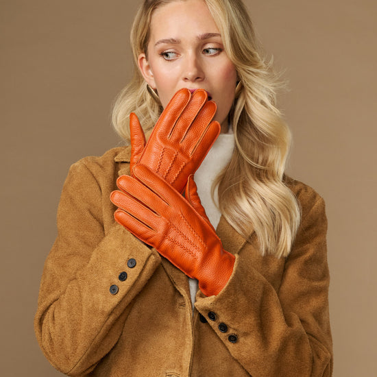 Orange leather gloves at face with stitched fingers and soft lined cuffs, nose and mouth covered