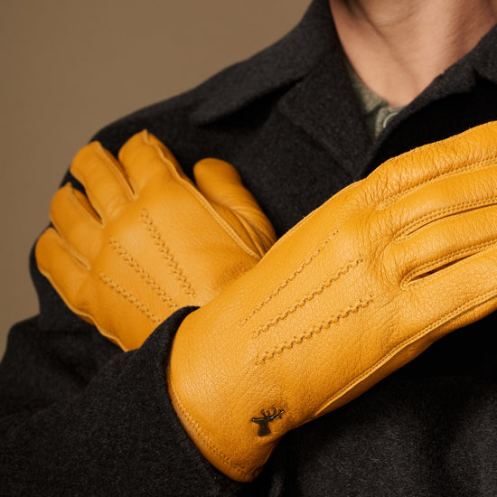 Yellow leather gloves, close-up of palm and finger seams; gray cuff lining
