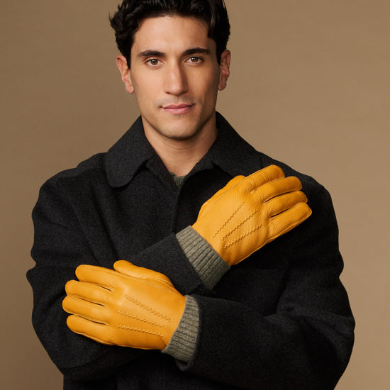 Yellow leather gloves with gray fleece cuffs, hands crossed in front